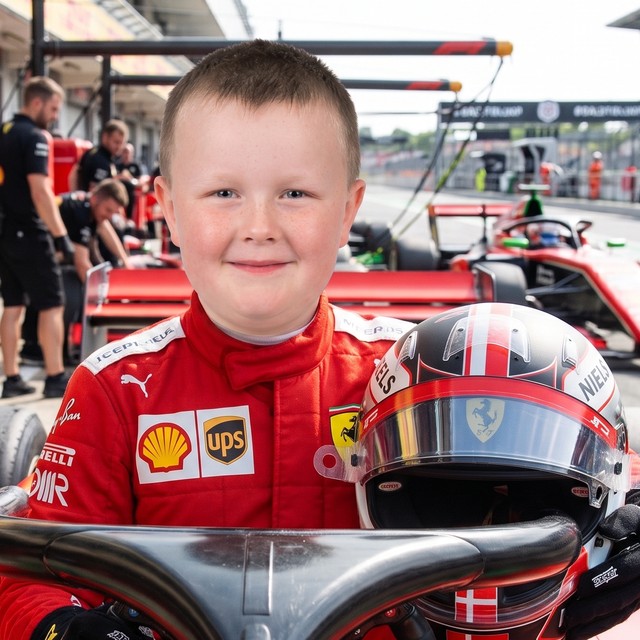 Otto i rød racerdragt med hjelm ved en rigtig Formel 1-racer